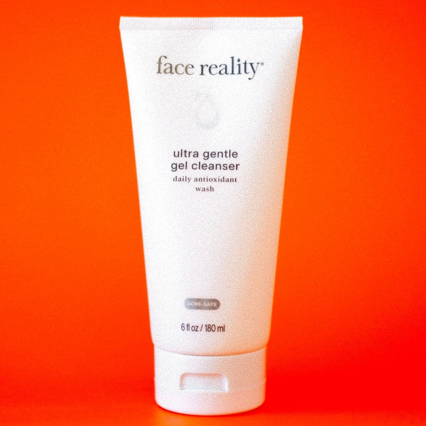 Tube of 'face reality' ultra gentle gel cleanser on an orange background from Clover Skin Bar