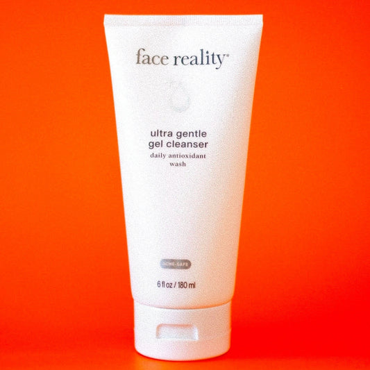 Tube of 'face reality' ultra gentle gel cleanser on an orange background from Clover Skin Bar