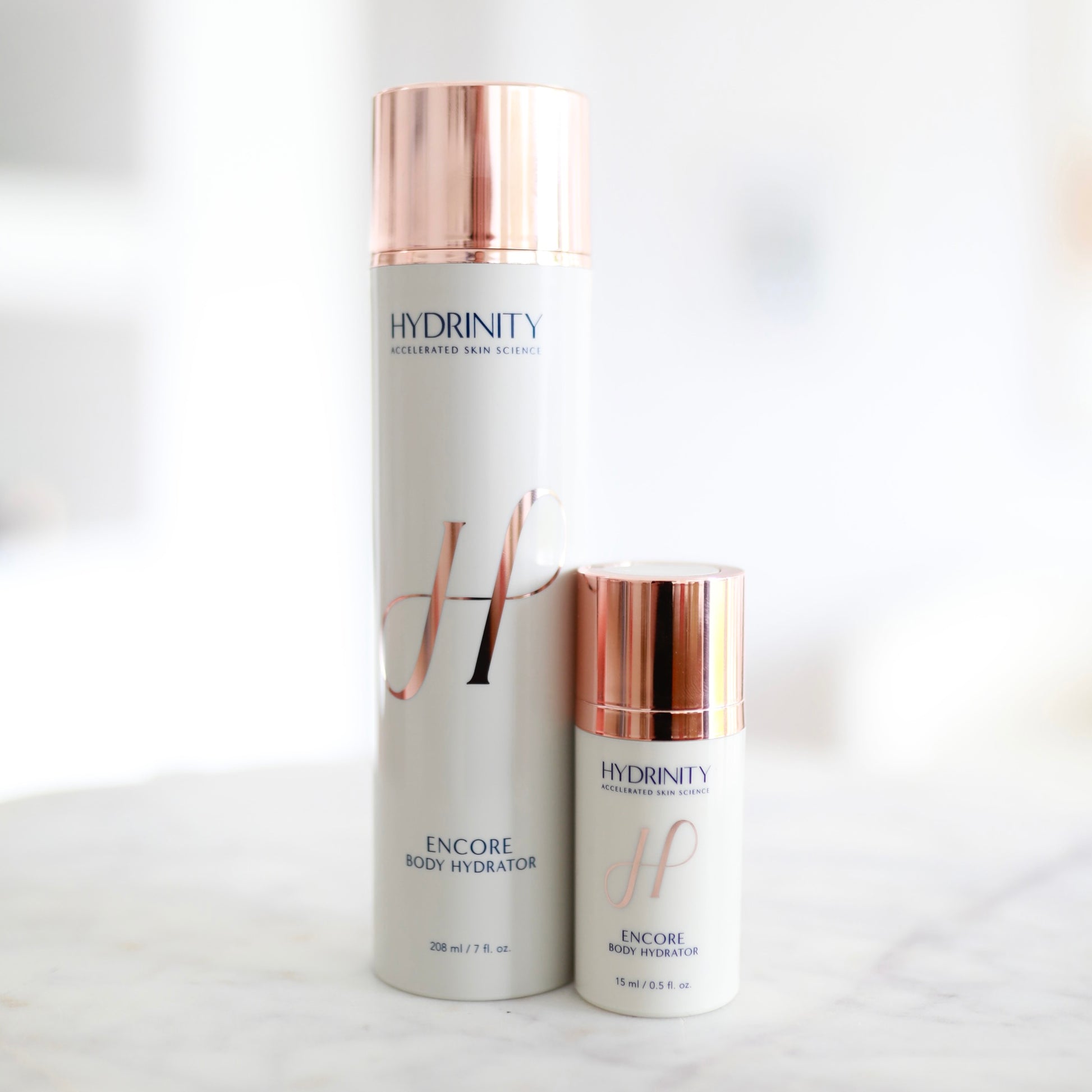 Encore Body Hydrator 7 oz up next to 15 mL travel size  - Hydrinity Body Moisturizer