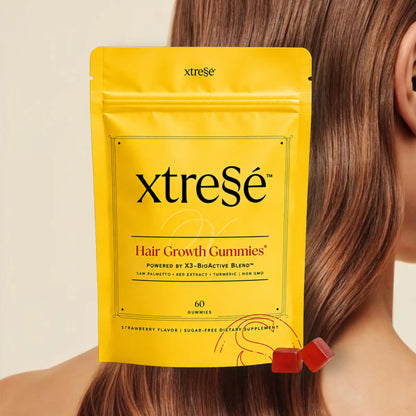XtreSé Hair Growth Gummies with two red gummy candies resting near the bottom right of the package. For sale at Clover Skin Bar.