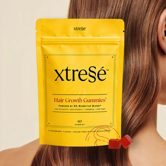 XtreSé Hair Growth Gummies with two red gummy candies resting near the bottom right of the package. For sale at Clover Skin Bar.